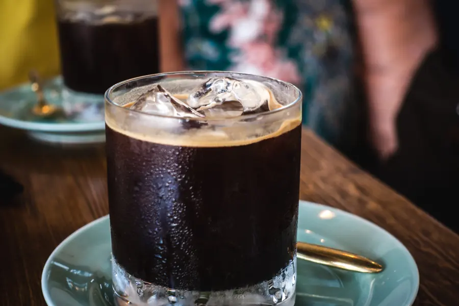 Glass of iced black coffee on a saucer