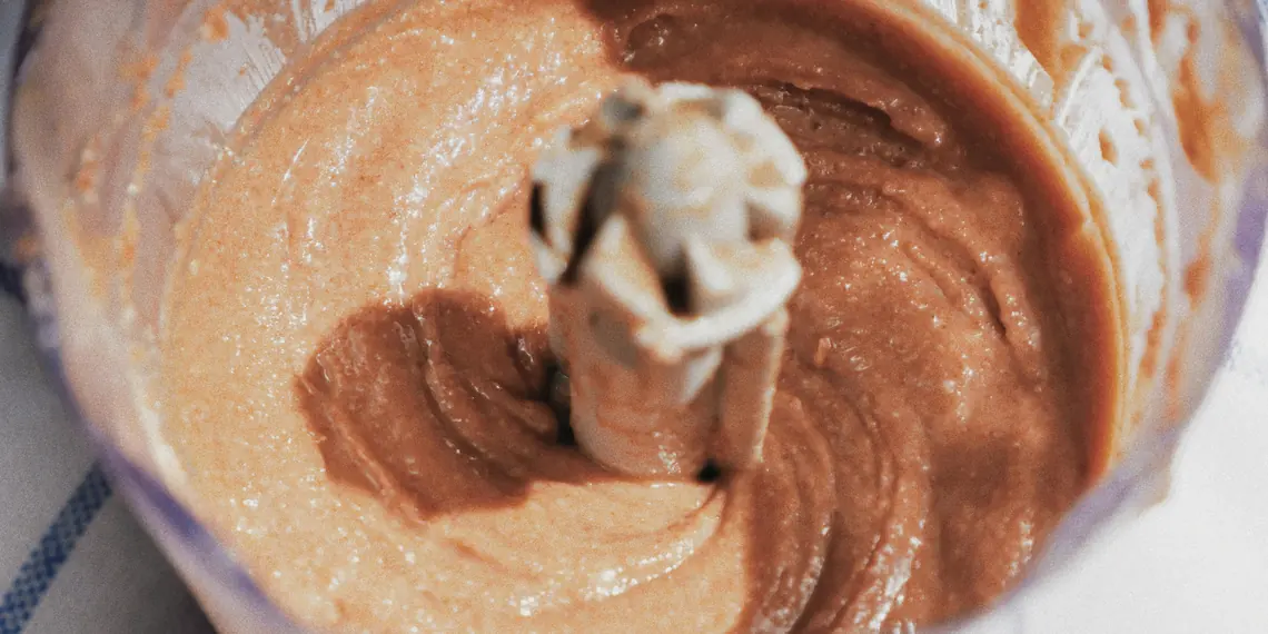 Creamy homemade nut butter being blended in a food processor bowl