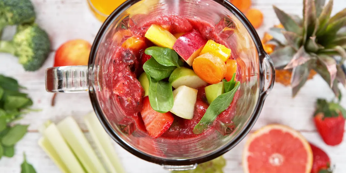 Overhead view of a blender jar filled with colorful fruit and vegetables